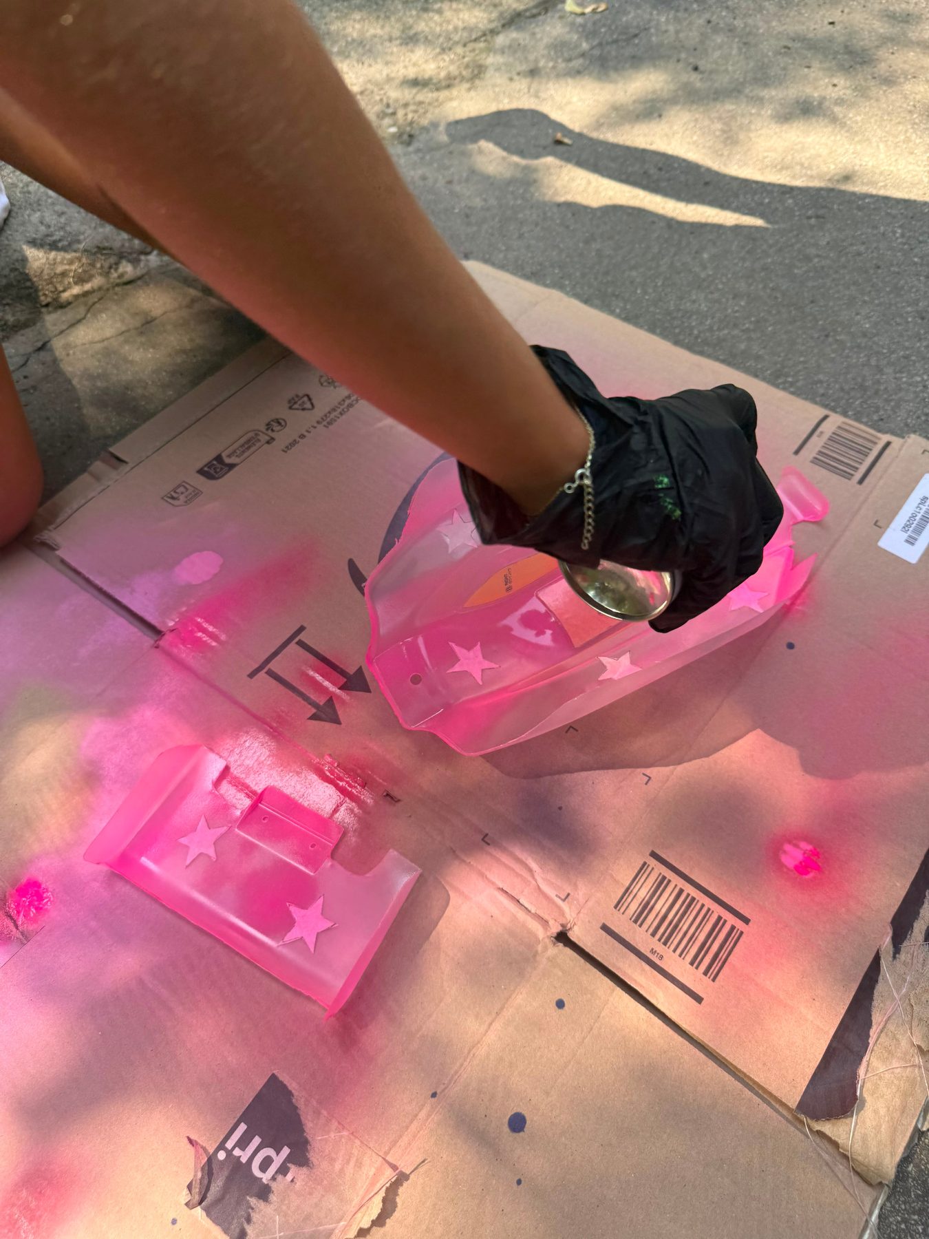 Participant spray painting a pink star-patterned RC buggy body outdoors in Vienna