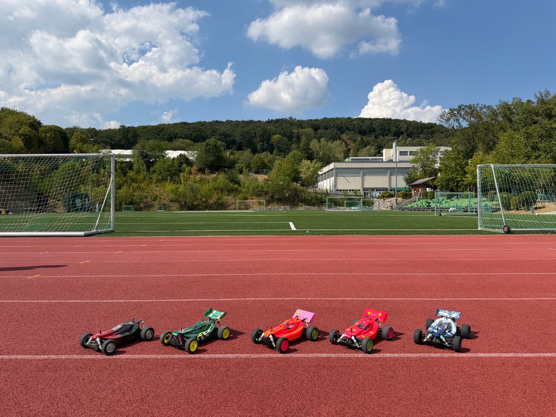 Five finished Tamiya RC buggies lined up on the athletics track at AIS Vienna